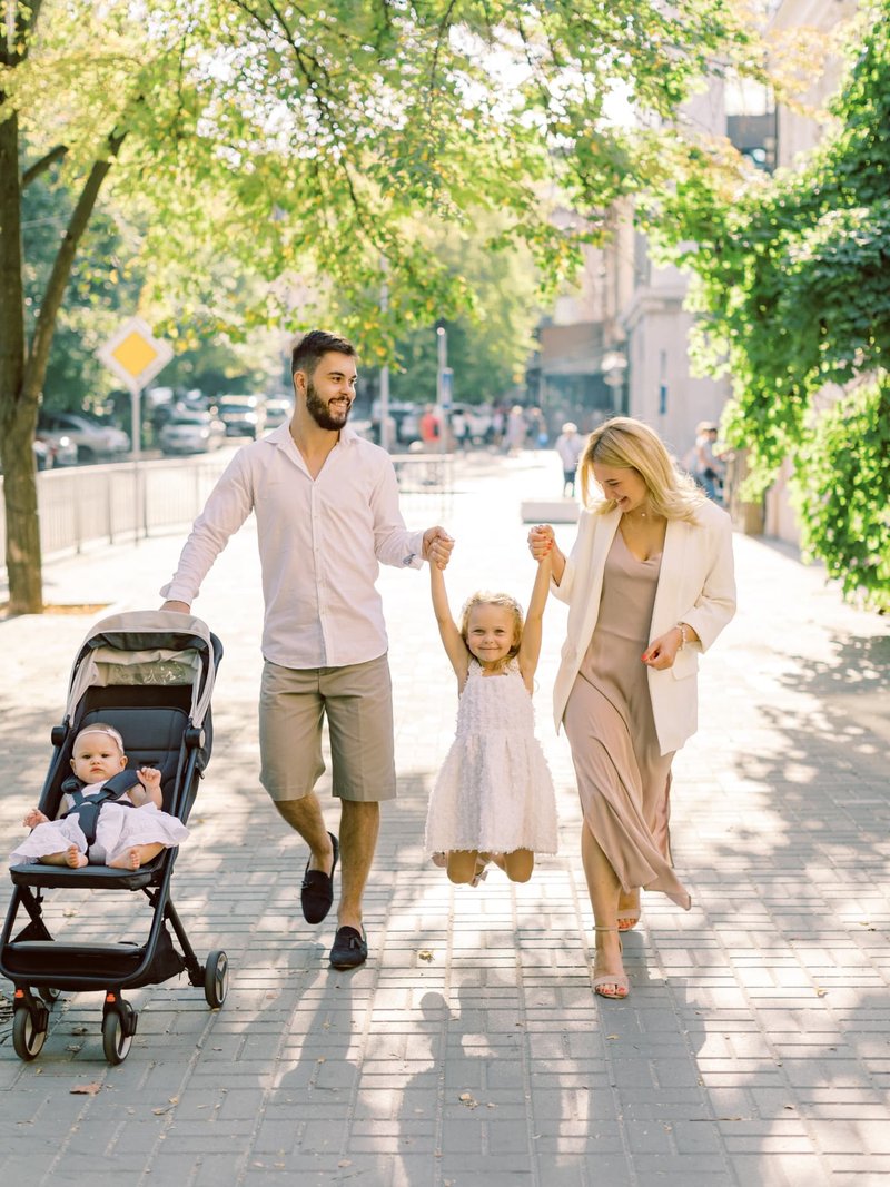 happy-family-strolling-800px Family walking together with a stroller on a tree-lined sidewalk.